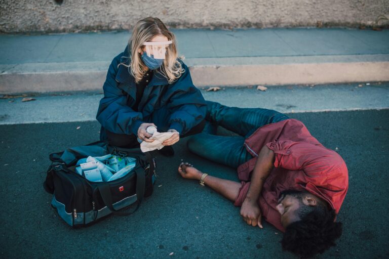 A paramedic tends to an unconscious man on a road, highlighting emergency services.